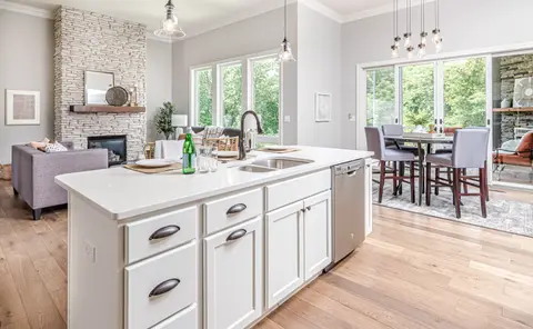 Bright open kitchen with white shaker cabinets, white quartz island countertop, stainless steel appliances, pendant lights