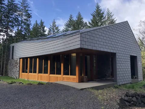 Contemporary home exterior featuring charcoal shingle siding, white metal soffit, wood-framed glass doors, and standing-seam