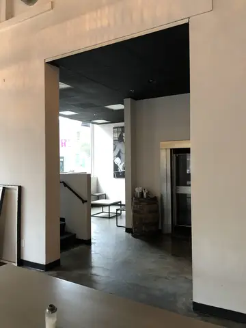 Polished concrete floor in open commercial interior with white drywall partitions and black ceiling above.