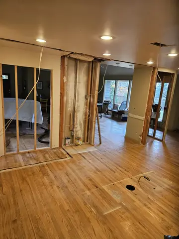 Bright commercial interior with newly installed wood plank flooring, recessed ceiling lights, glass-panel partition walls