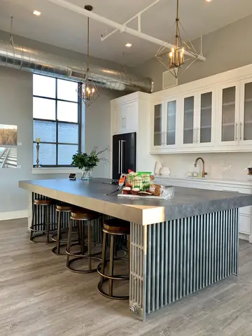 Modern kitchen with white upper cabinetry, gray lower island with wood countertop, three pendant lights, and large window