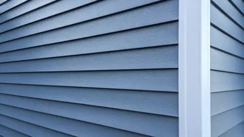 Horizontal fiber cement siding in blue-gray with crisp white vertical trim corner, demonstrating clean installation and